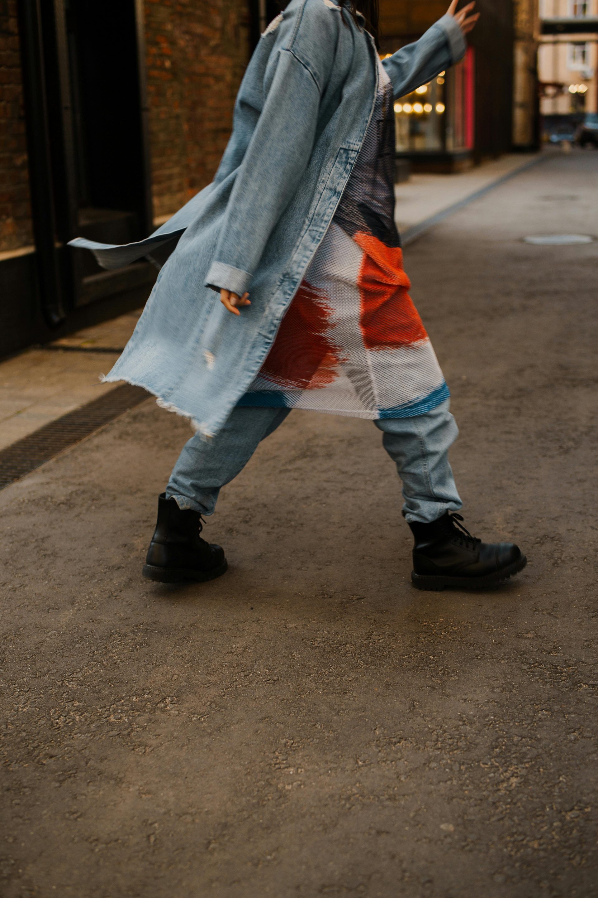 Person walking on city street in a denim coat showcasing urban fashion style.