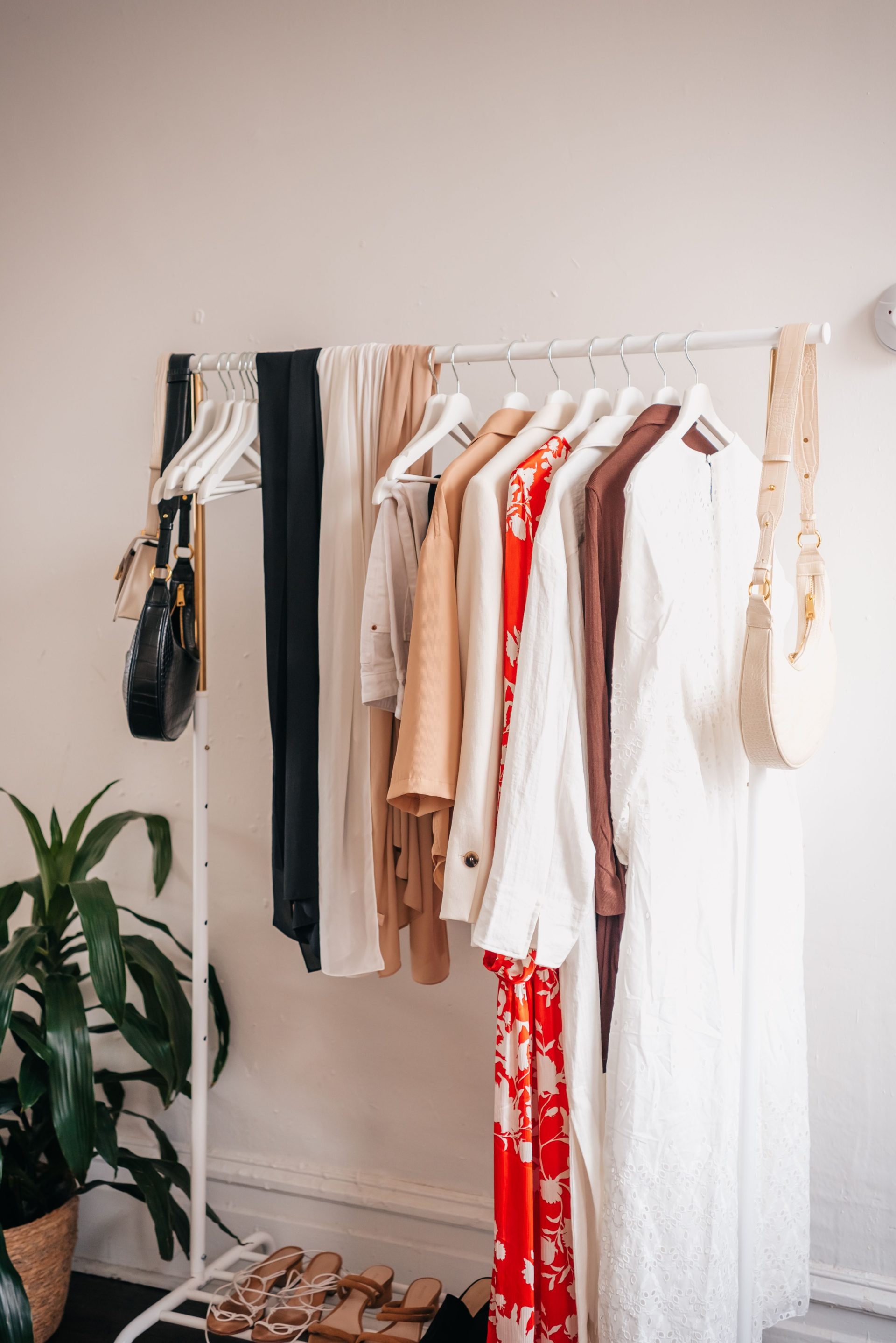 Stylischer Kleiderständer mit Kleidern und Accessoires im Interieur einer Boutique.